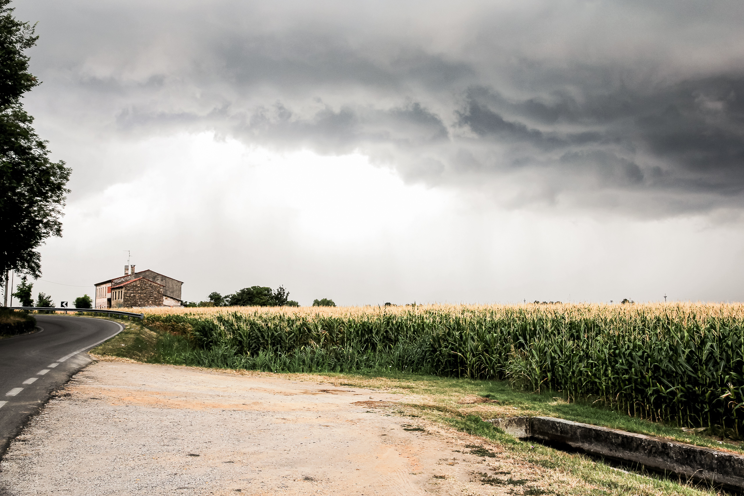 Der Regen kommt quer über die Felder – Unterstand suchen beim Haus an der Straße